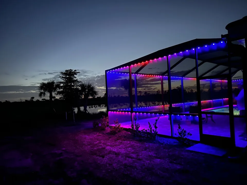 Pool cage seen from outside at sunset in magenta and blue