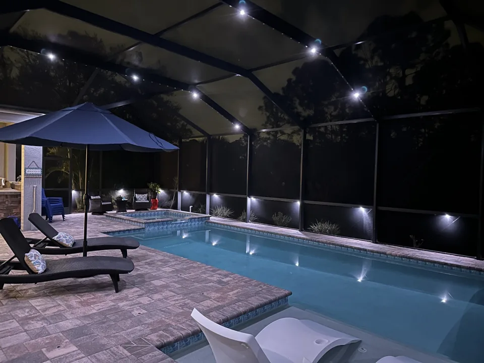 Pool cage in warm white with an umbrella and loungers