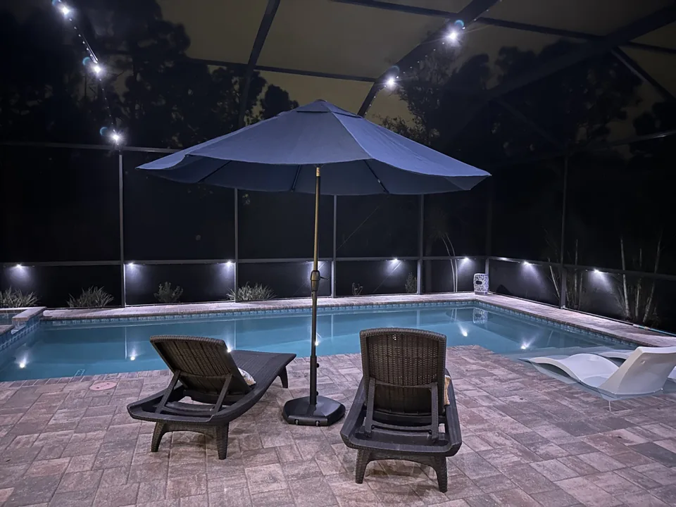 Wide view of a pool cage lit in warm white