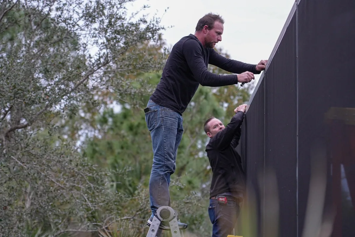 Two installers on ladders fitting channel